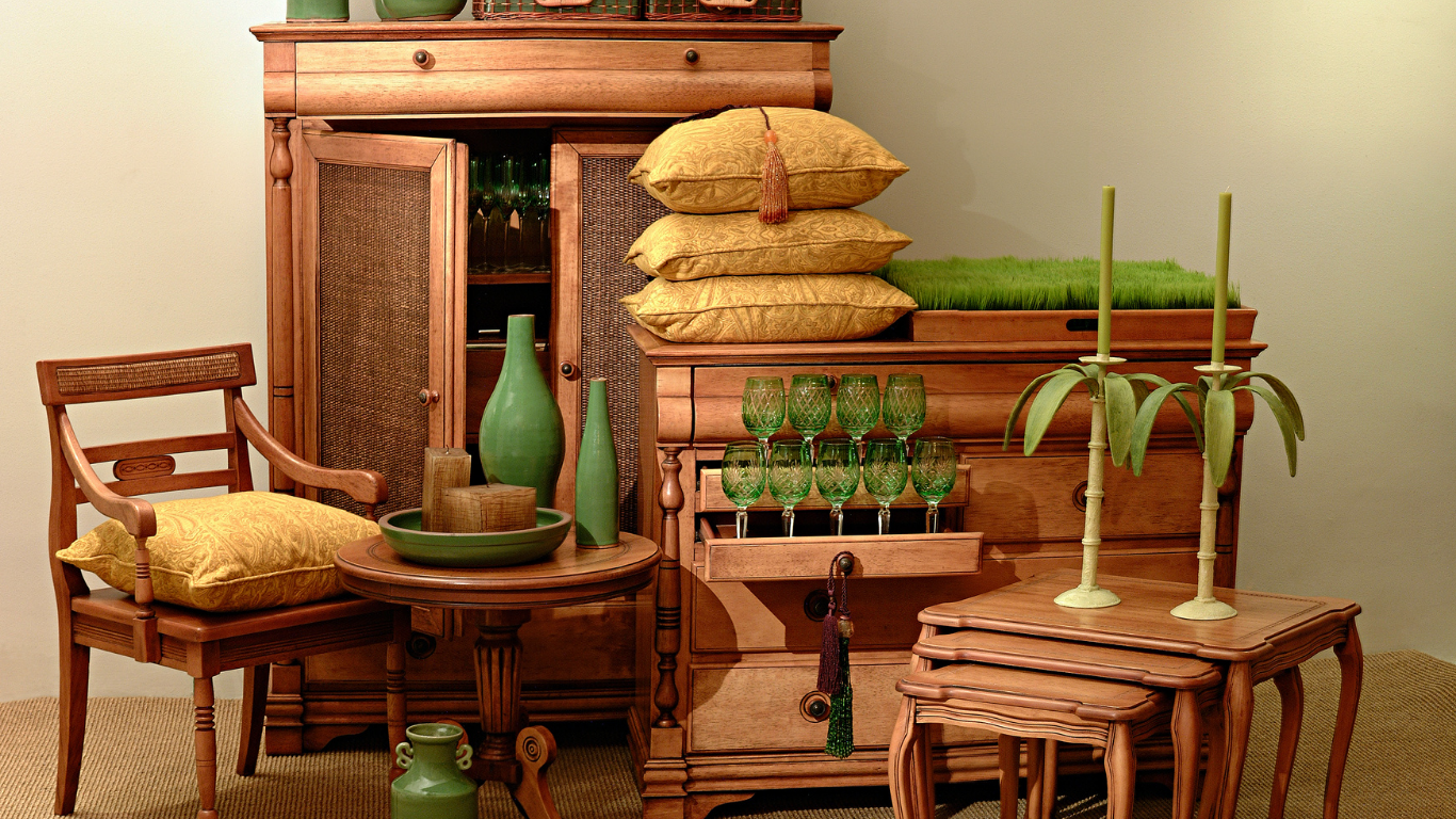 Wooden furniture vignette with pillows, green vases, and plants.