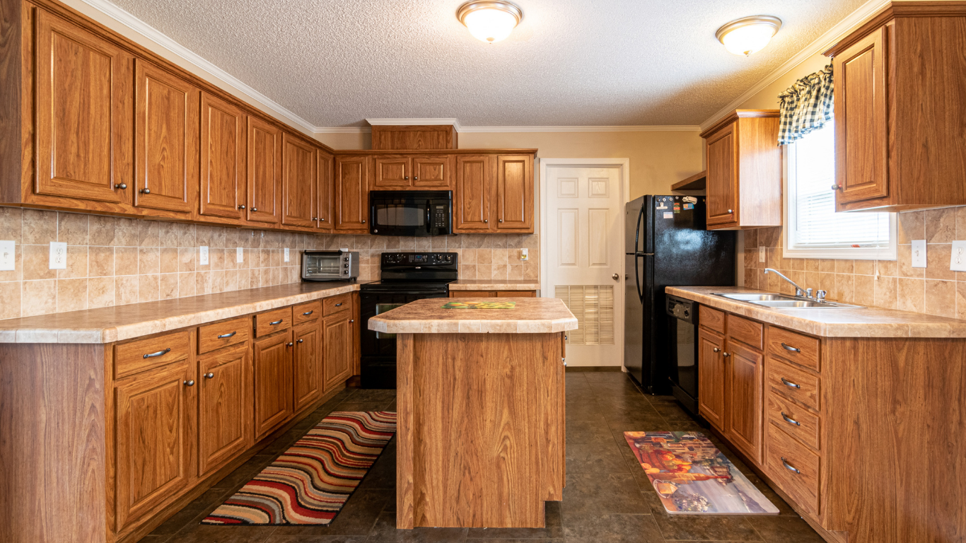 Kitchen with oak cabinets, beige countertops, black appliances, and a central island.