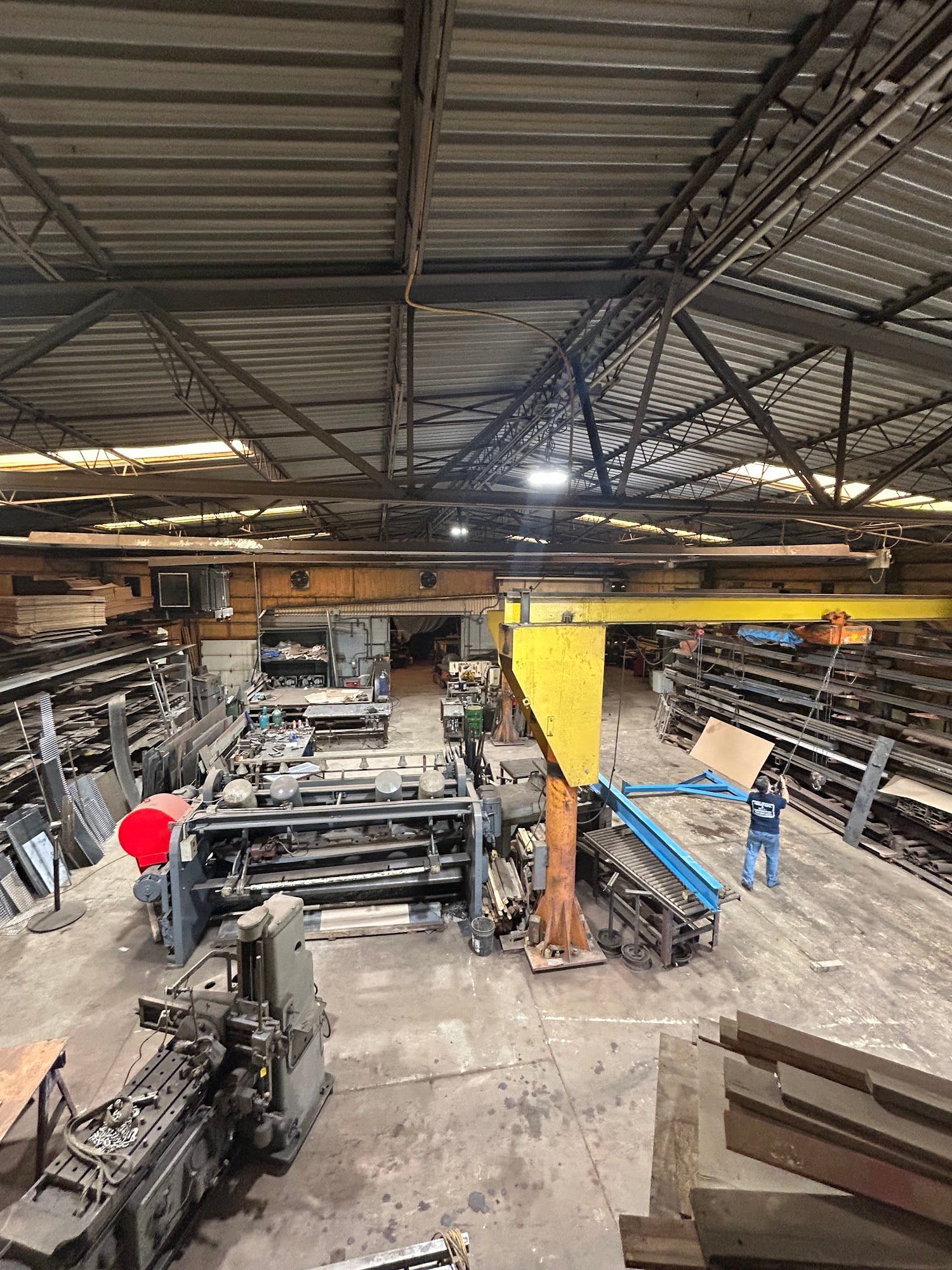 Large warehouse with metalworking machinery and materials. Overhead crane.