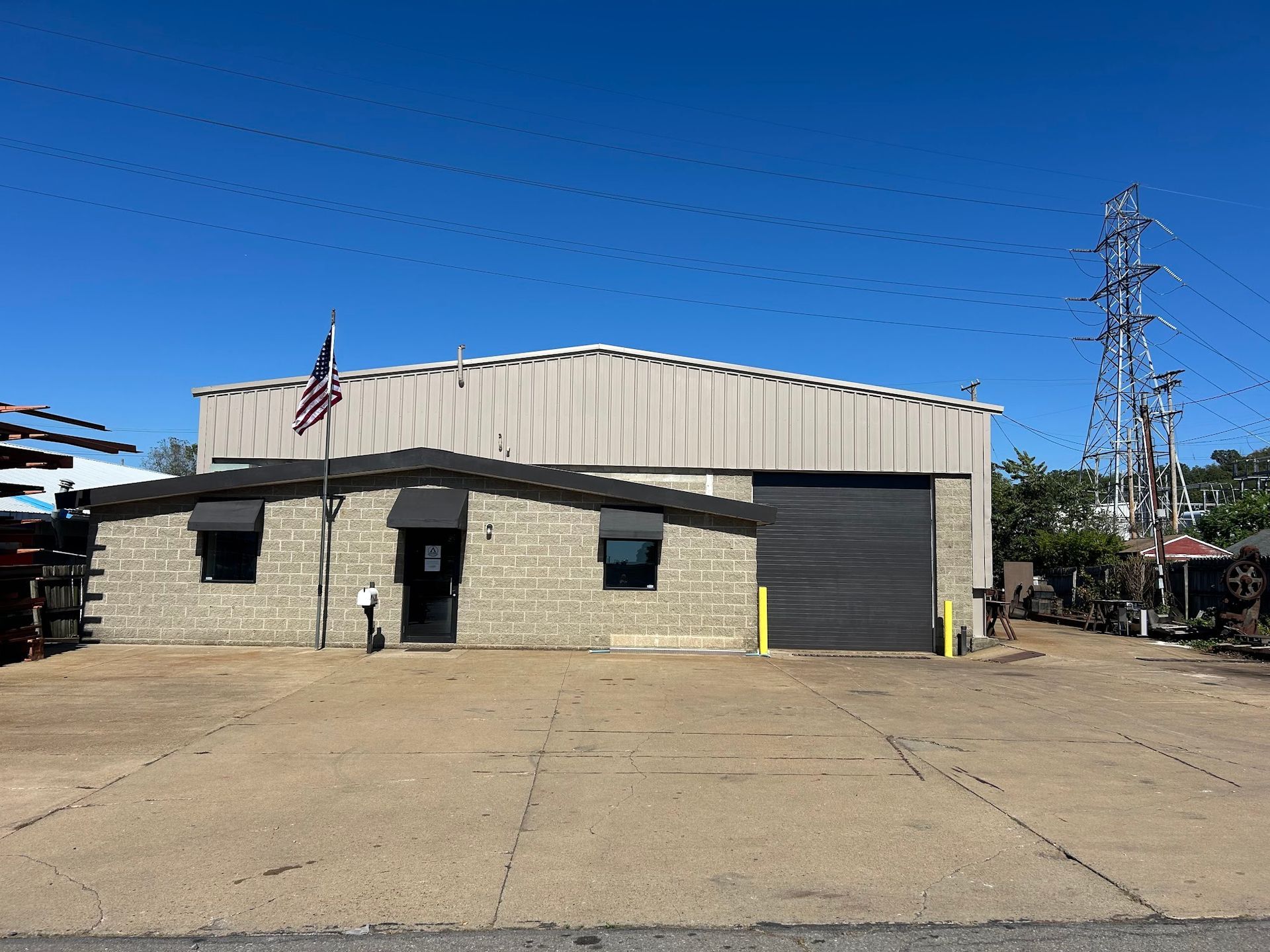 Brick building with garage door, awning, and American flag on a sunny day.