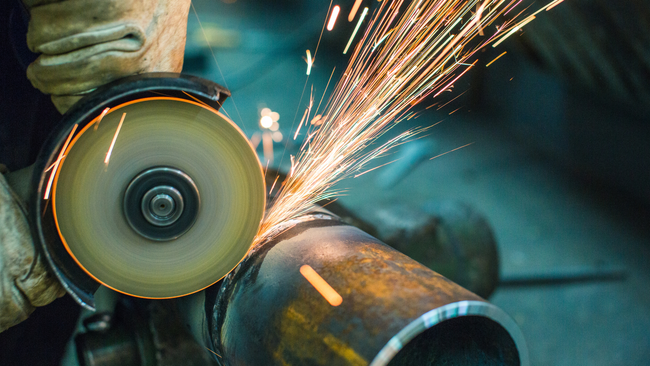 Metal machining equipment with a rotating part being ground.