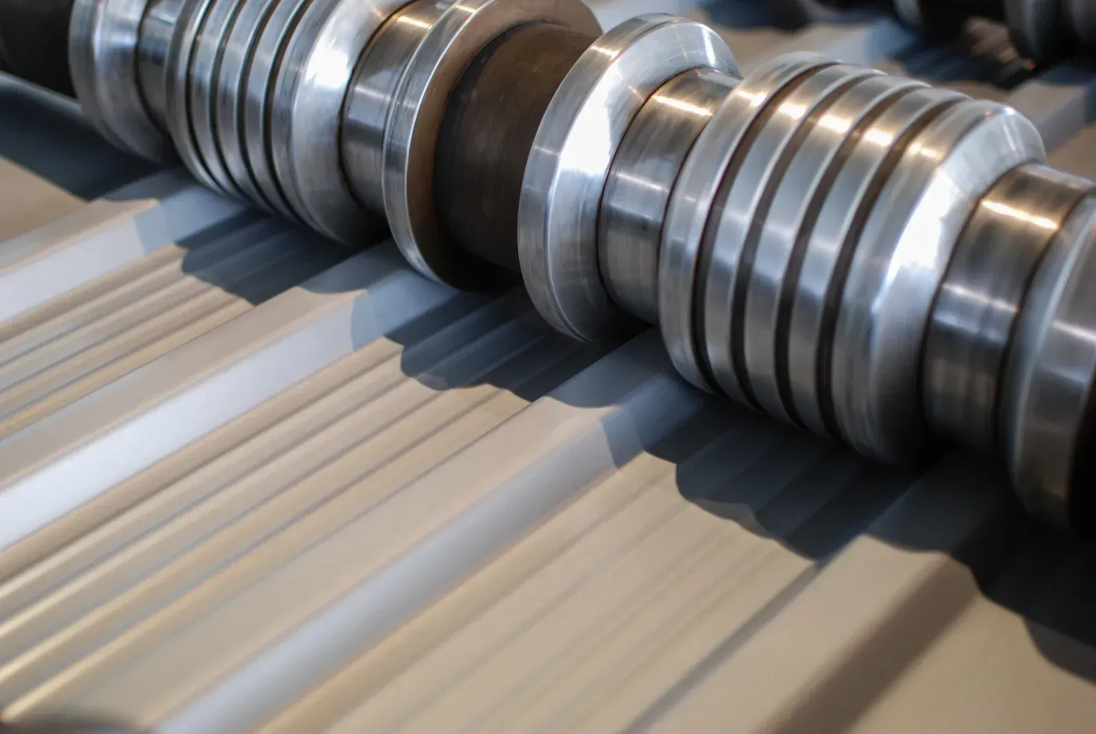 Metal rollers shaping corrugated metal roofing material.