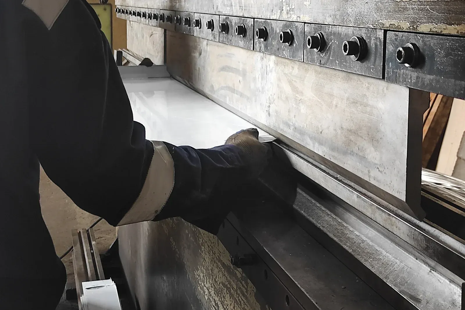 Person bending metal sheet on industrial press brake.