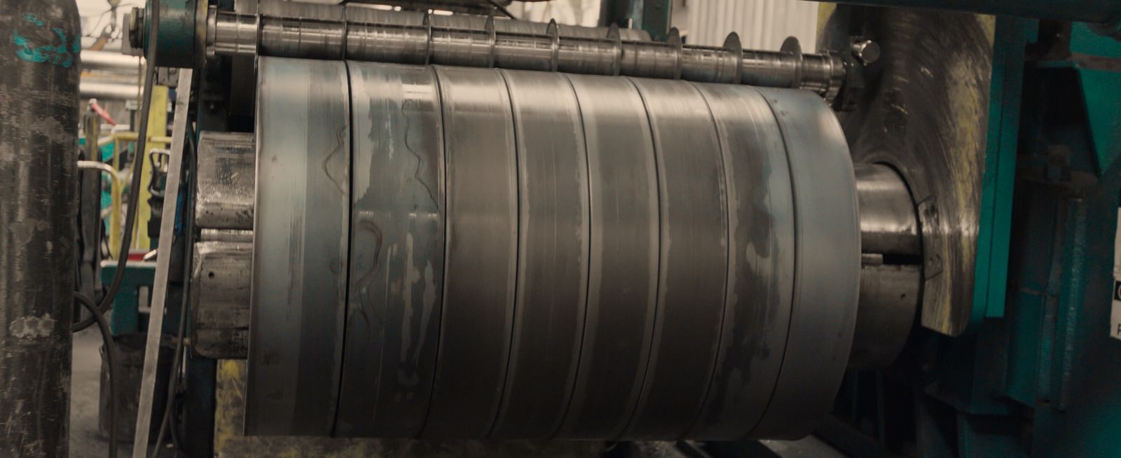 Metal sheets being cut by industrial machinery in a factory.