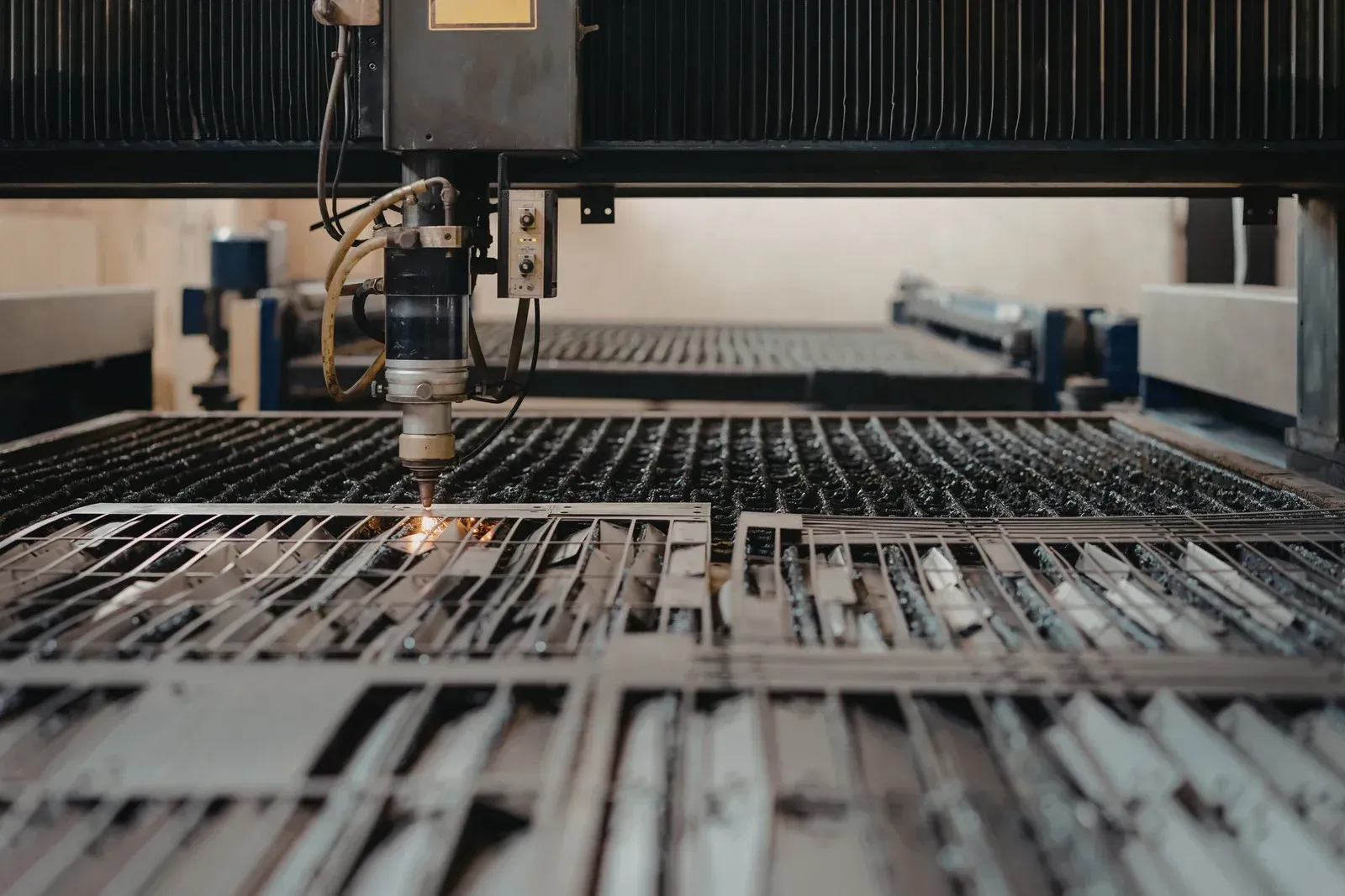Laser cutter cutting metal sheets in a factory, sparks flying.