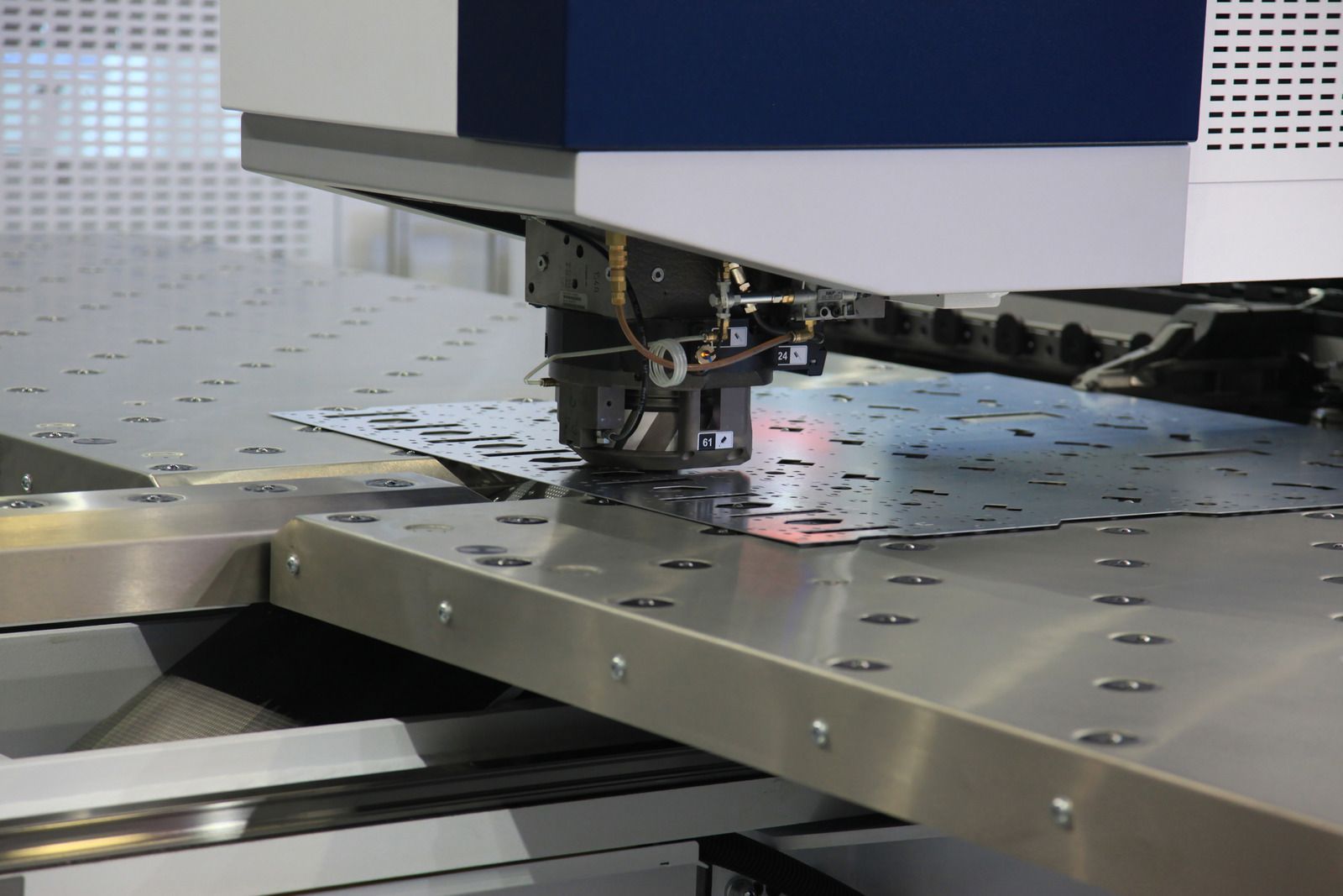 Metal punch machine in operation, cutting shapes from a sheet of metal.