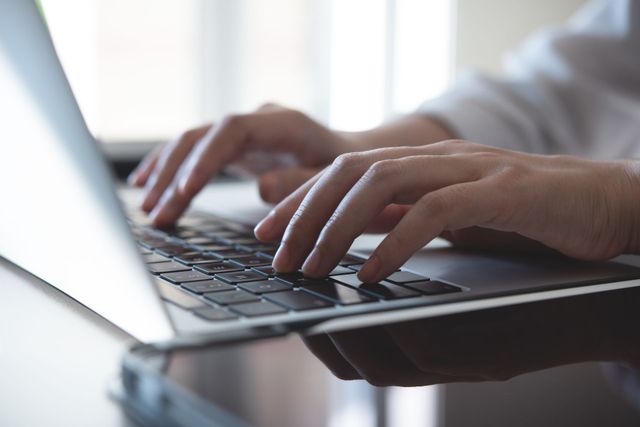 A person is typing on a laptop computer.