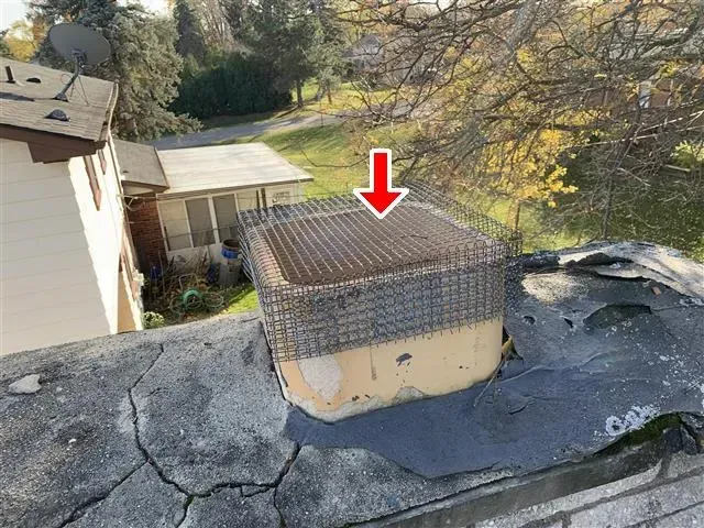 Chimney cap on a roof with an arrow pointing to it.