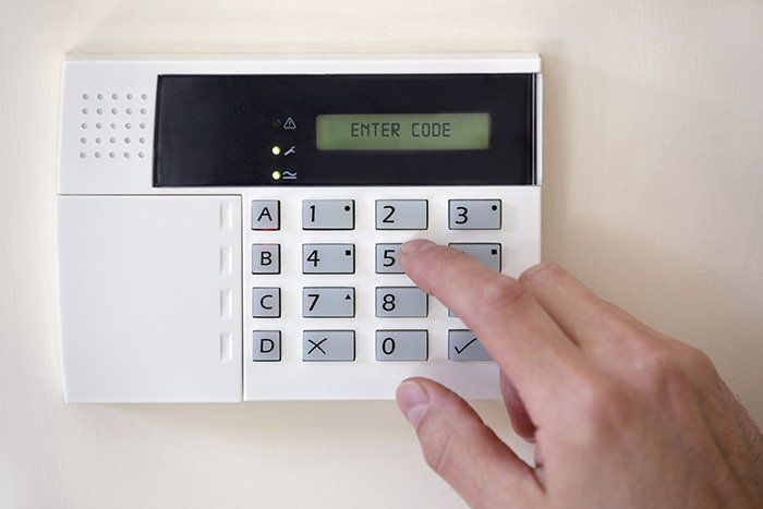 A person is pressing a button on a security system to enter a code.