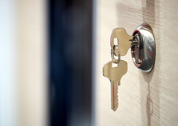 A close up of two keys in a lock on a door.