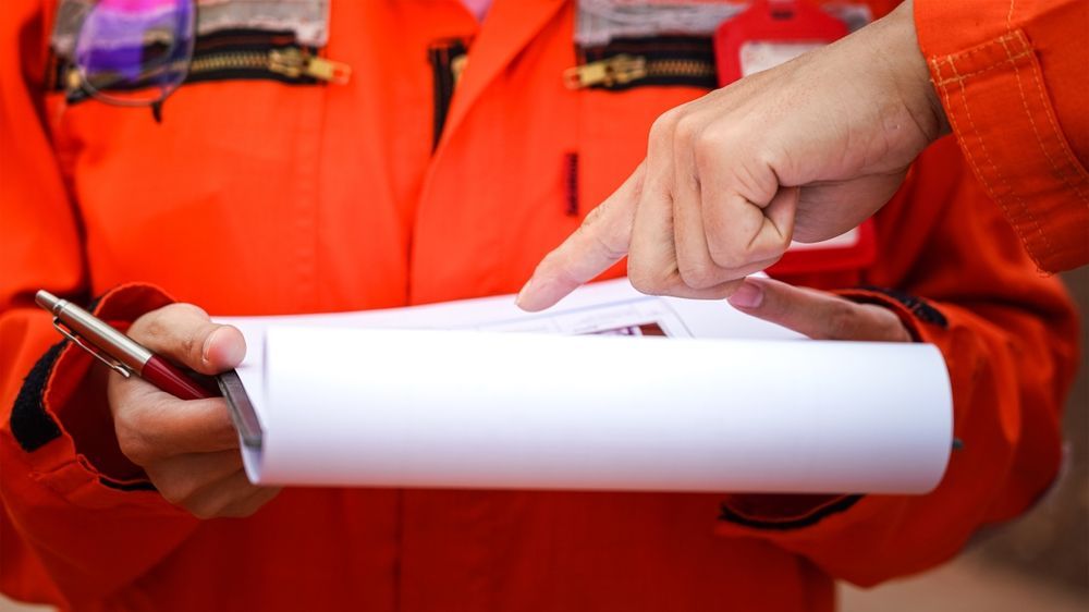 Two People in Orange Work Uniforms Reviewing a Document — Wendy's Safety Services In Daly River, NT
