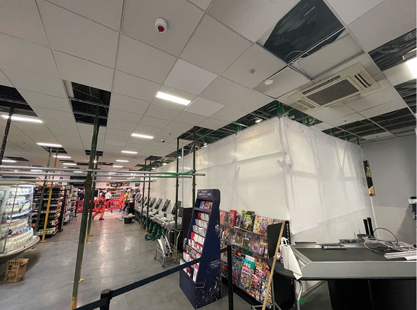 A store with a broken ceiling and a magazine stand.