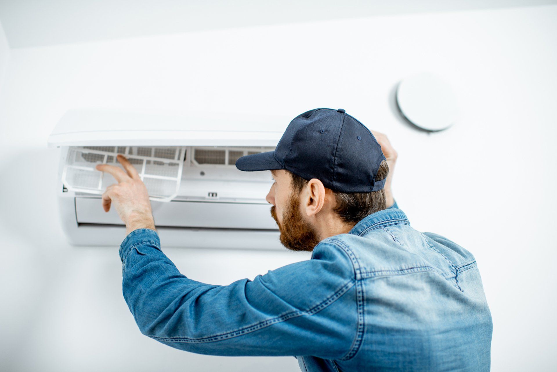 Man Repairing AC. Controlled Heating & Cooling Has Experienced HVAC Contractors in Mid-MO.