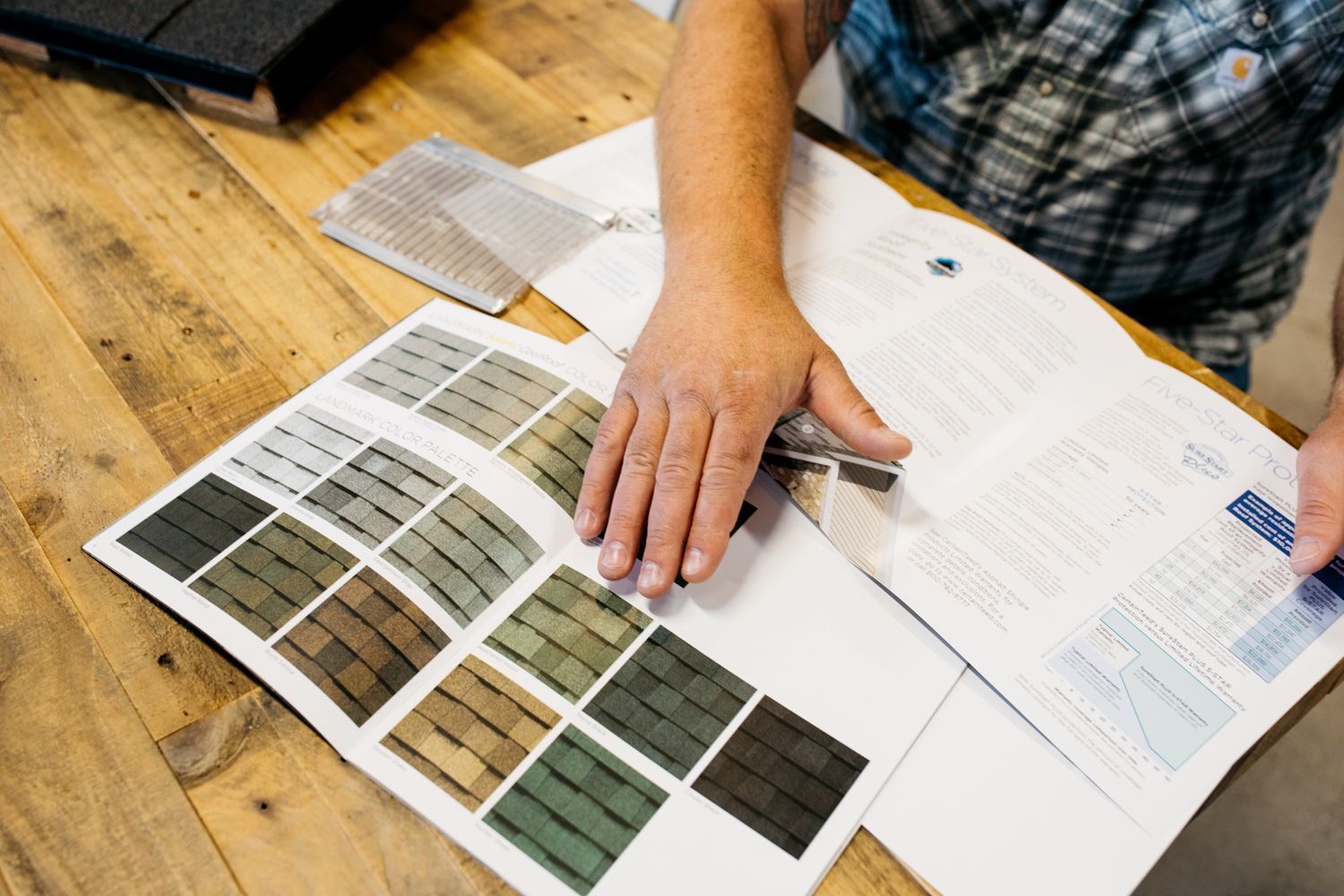 A person is looking at a brochure on a wooden table.