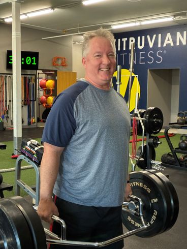 Man lifting a 45-pound plate with a trap bar for deadlifts in gym