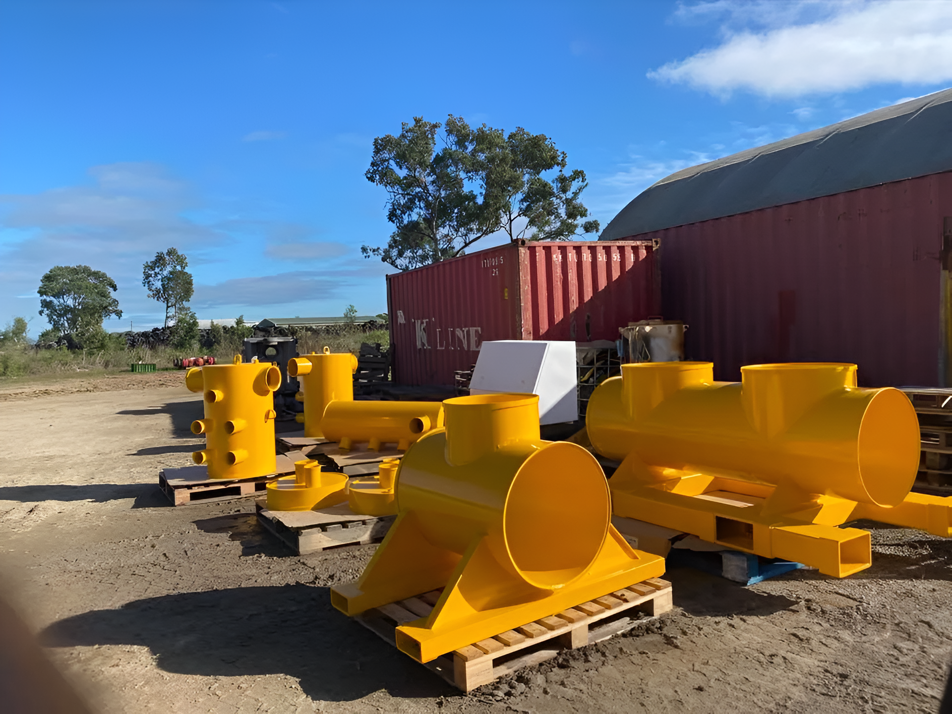 Yellow Metal Industrial Parts on Pallets in a Yard, Under a Blue Sky — All Blast and Paint in Bakers Creek, QLD