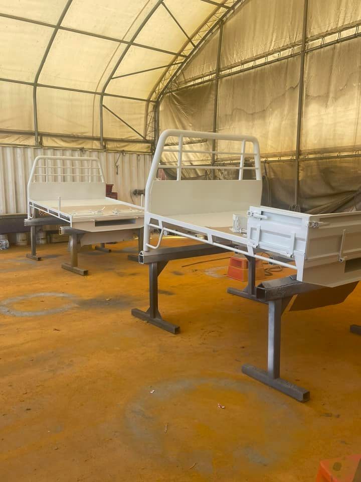 Two White Truck Beds on Stands Inside a Workshop — All Blast and Paint in Marian, QLD