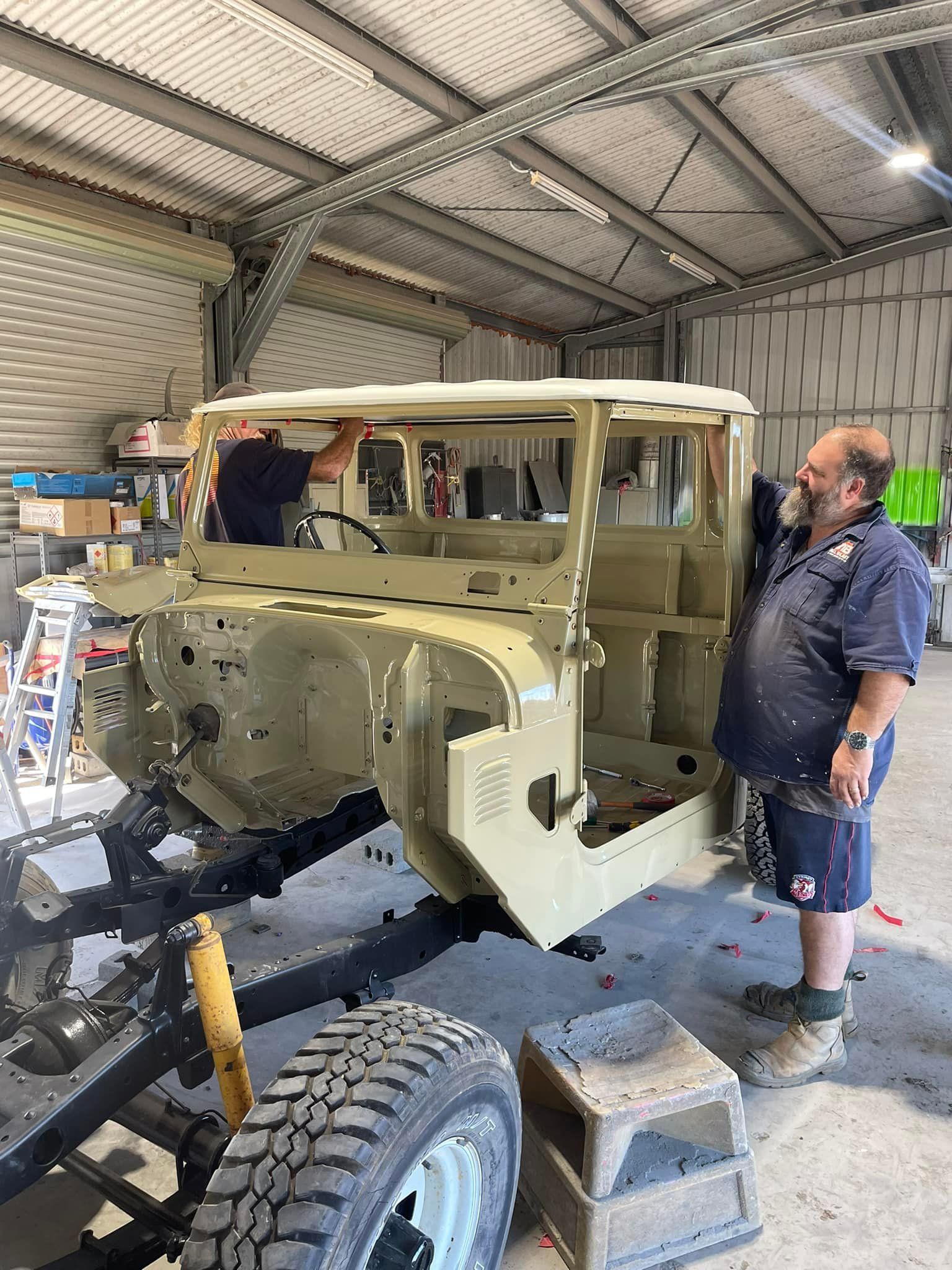 Men Working on a Beige and Black Vintage Land Cruiser in a Garage — All Blast and Paint in Bakers Creek, QLD