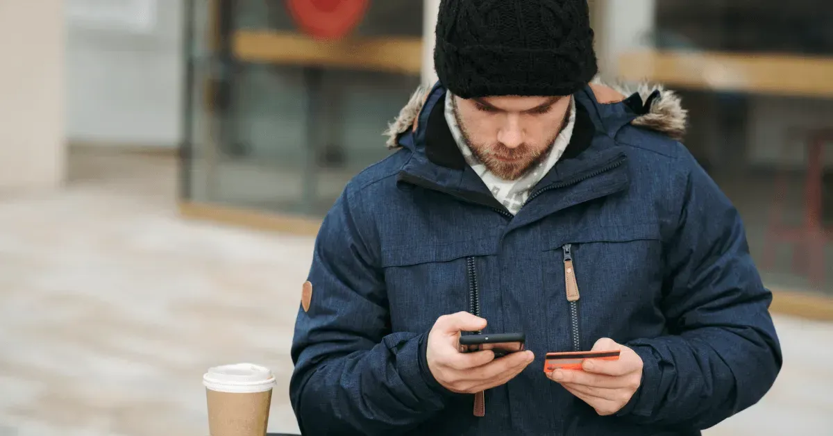 A man is sitting at a table looking at his cell phone.