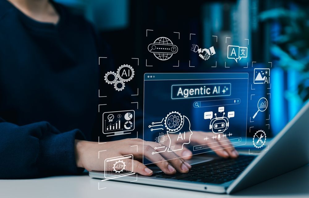 Hands typing on a laptop with an “Agentic AI+” digital interface overlay on a blue-toned screen