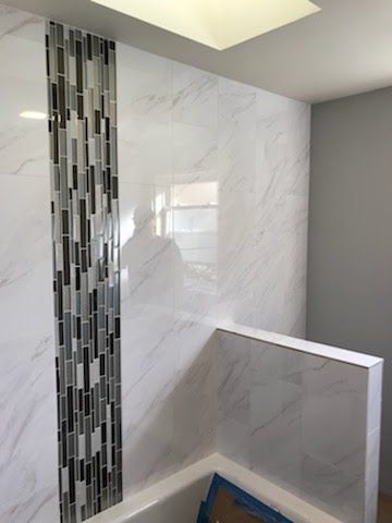 A bathroom with a bathtub and a tiled wall.