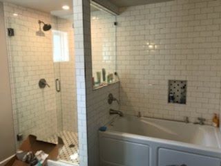 A bathroom with a tub, shower, and mirror.