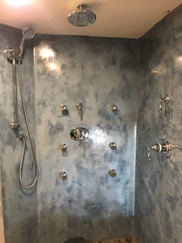 A shower with a shower head and faucets on the wall.