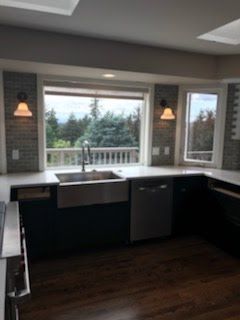 A kitchen with a sink, dishwasher, and window.