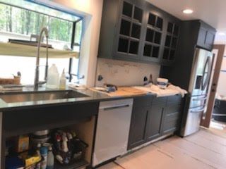 A kitchen with a sink, dishwasher, refrigerator, and window.