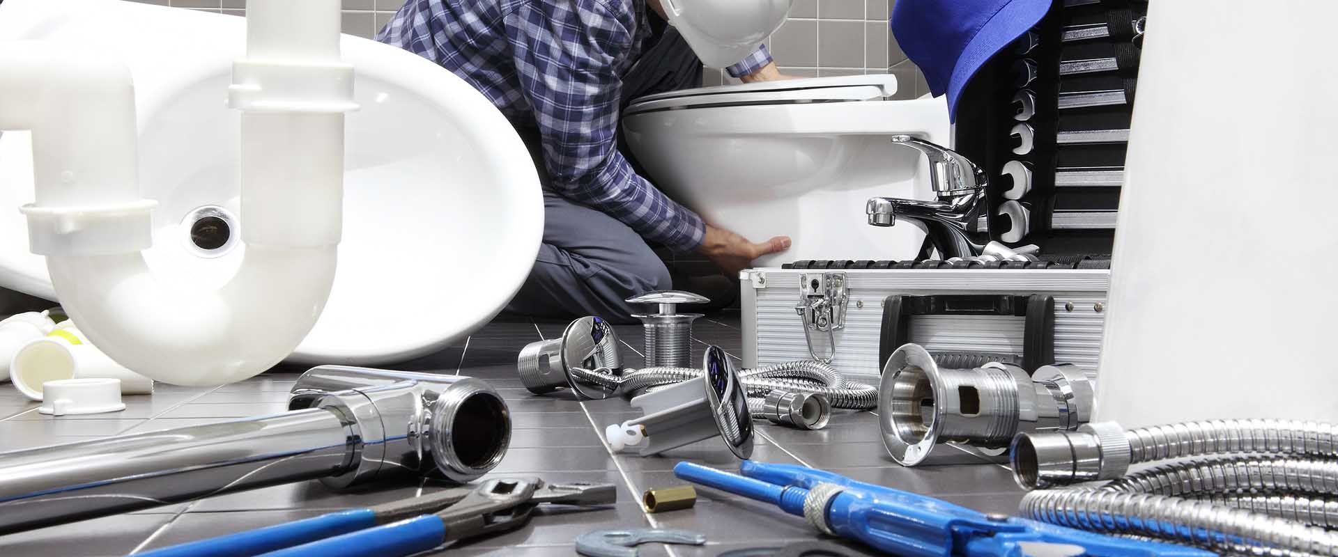 A plumber is working on a toilet in a bathroom.