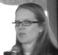 Woman with glasses speaking into a microphone.