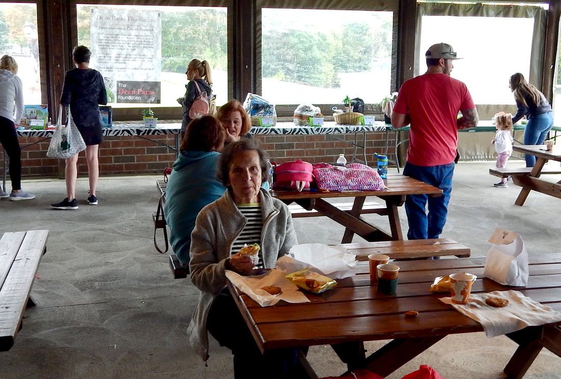 People eating at picnic tables in a covered outdoor area.