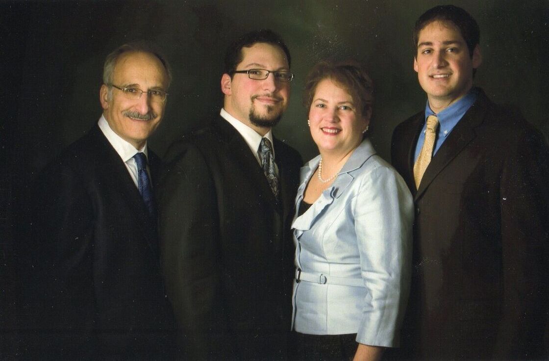 Four people posing for a portrait; all are wearing suits and ties.