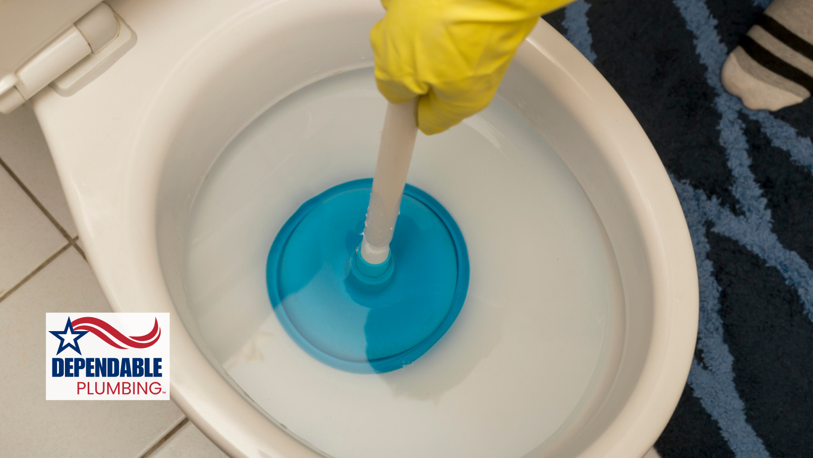 Person in yellow gloves using a blue plunger to unclog a white toilet.