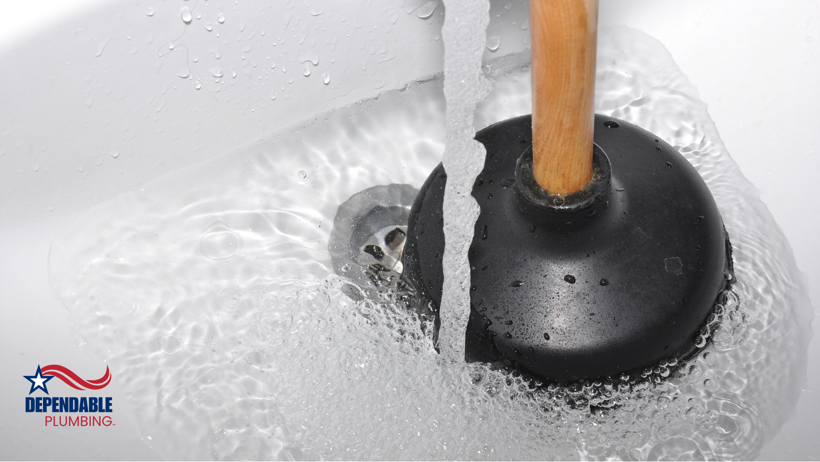 A plunger with a wooden handle is in a sink with water coming out of it.