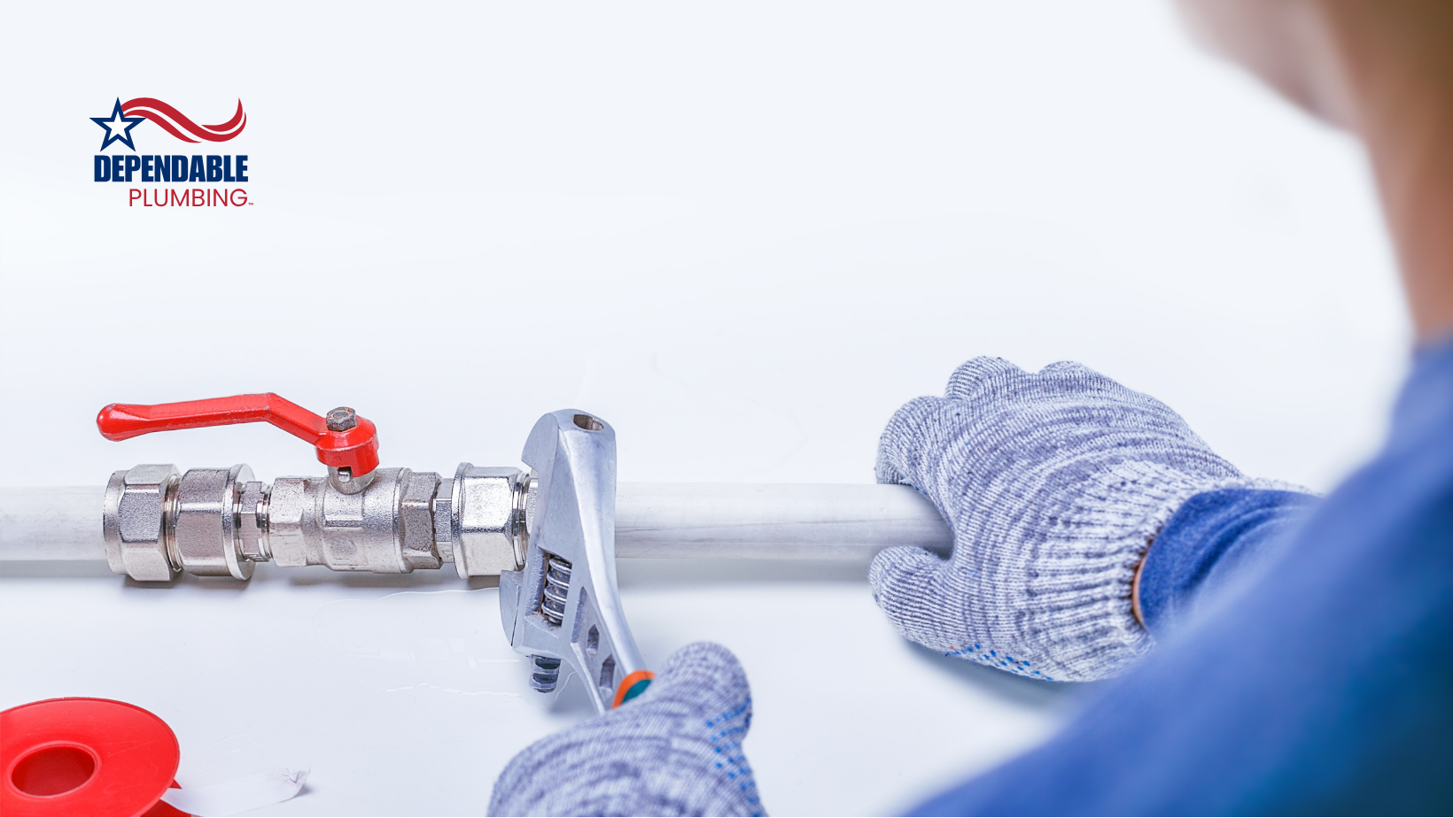 A man wearing gloves is working on a pipe with a wrench.