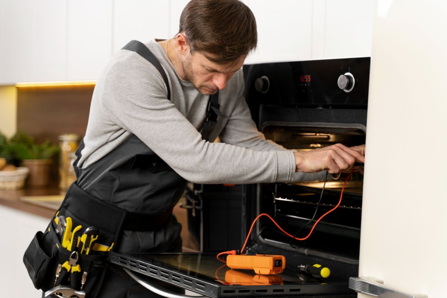 A man is fixing an oven in a kitchen.