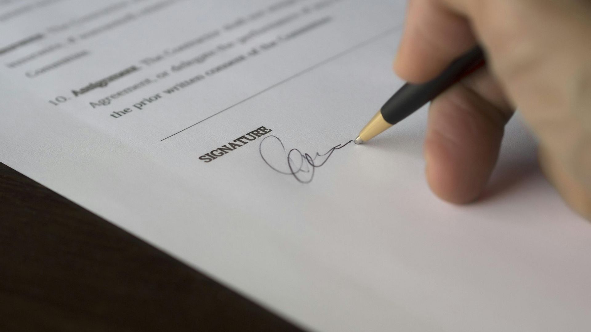 A person is signing a document with a pen.