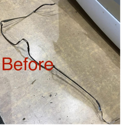 A black, bent wire on a concrete floor, labelled 