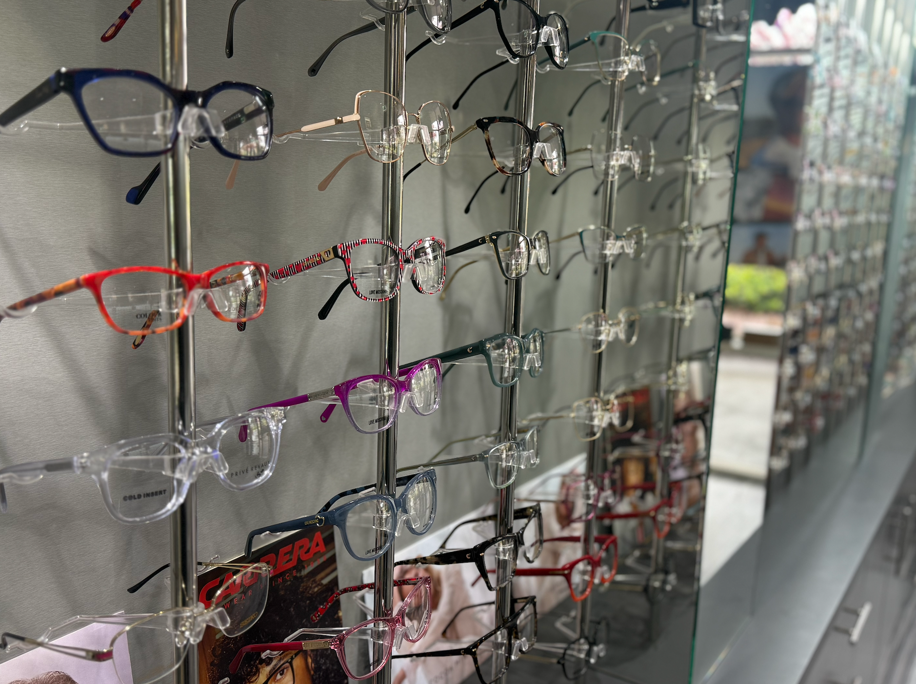 A Person is Holding a Pair of Glasses in Front of a Wall of Glasses — Eyepower In Picton, NSW