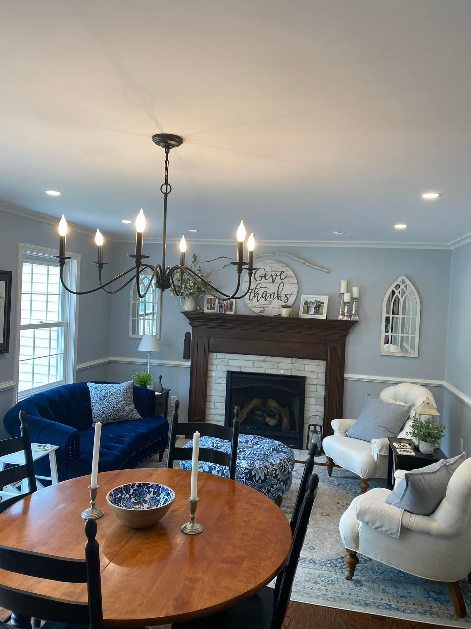 A living room with a table , chairs , a fireplace and a chandelier.