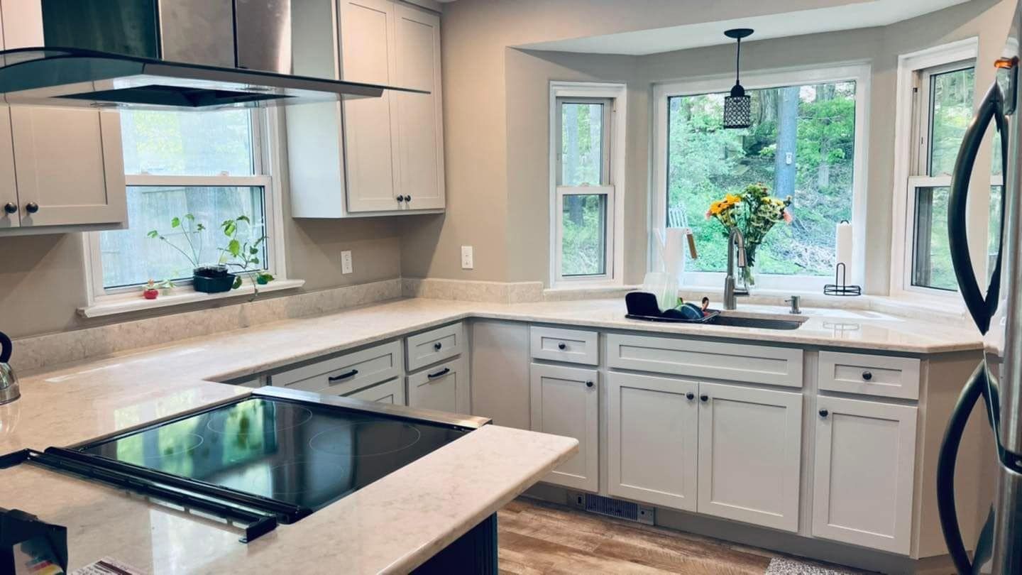 A kitchen with white cabinets , stainless steel appliances , a stove top oven , and a sink.