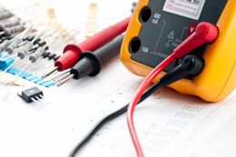 A yellow multimeter is sitting on top of a piece of paper.