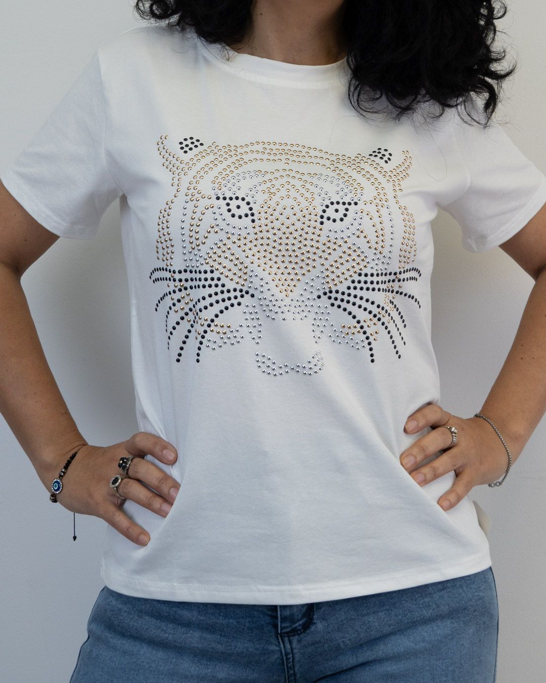 Mujer que lleva una camiseta blanca con un diseño de tigre de diamantes de imitación, con las manos en las caderas.