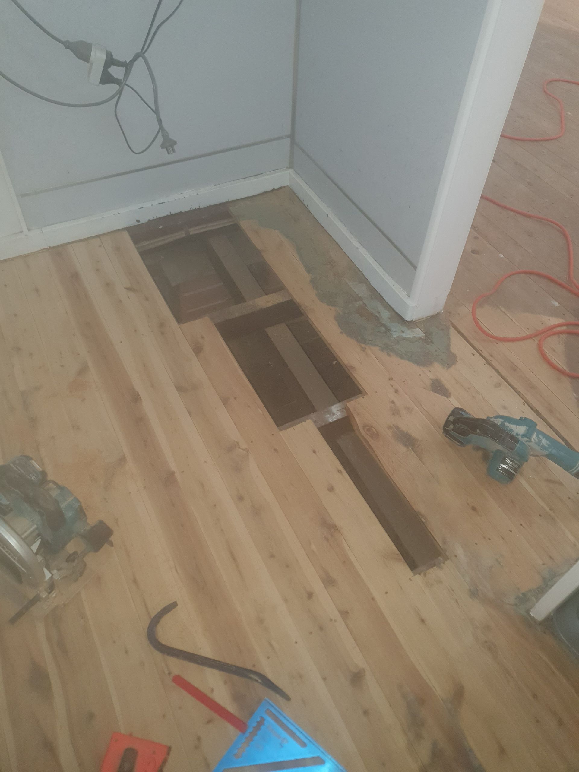 A wooden floor with a hole in it and tools on it. A wooden floor with a hole in it and tools on it.