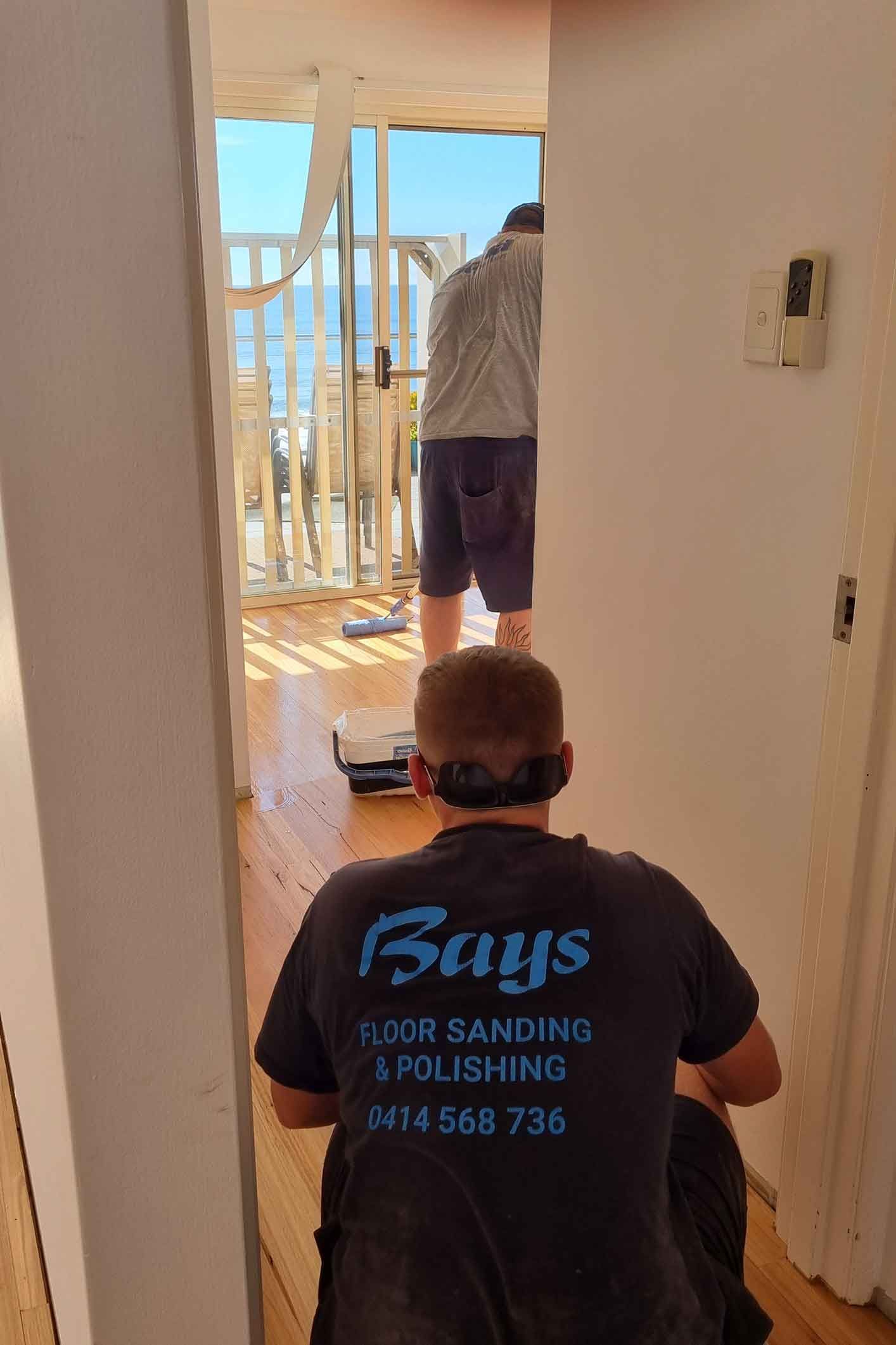 A man is sanding a wooden floor in a room. A man is sanding a wooden floor in a room.