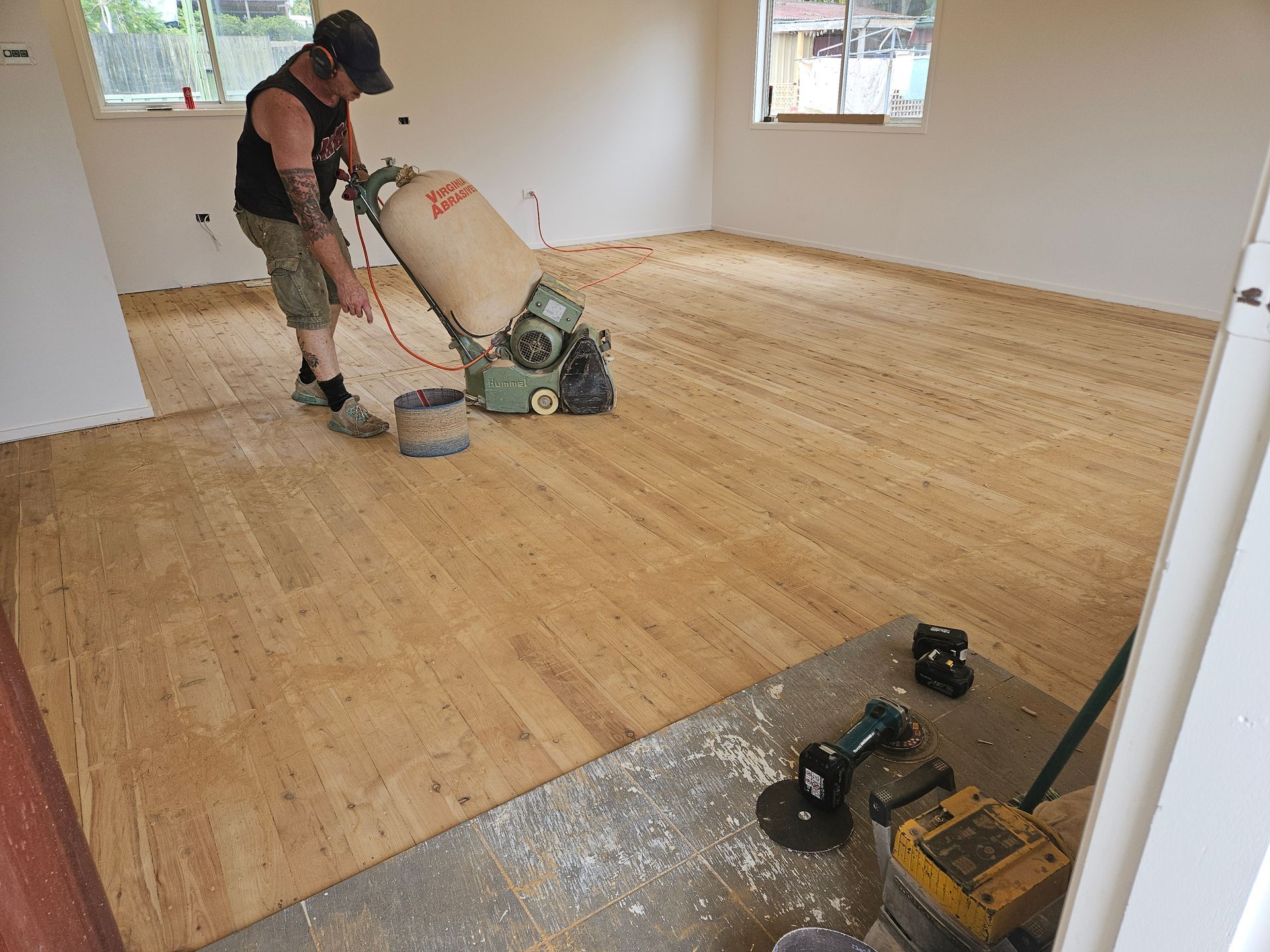 A man is sanding a wooden floor with a machine. A man is sanding a wooden floor with a machine.