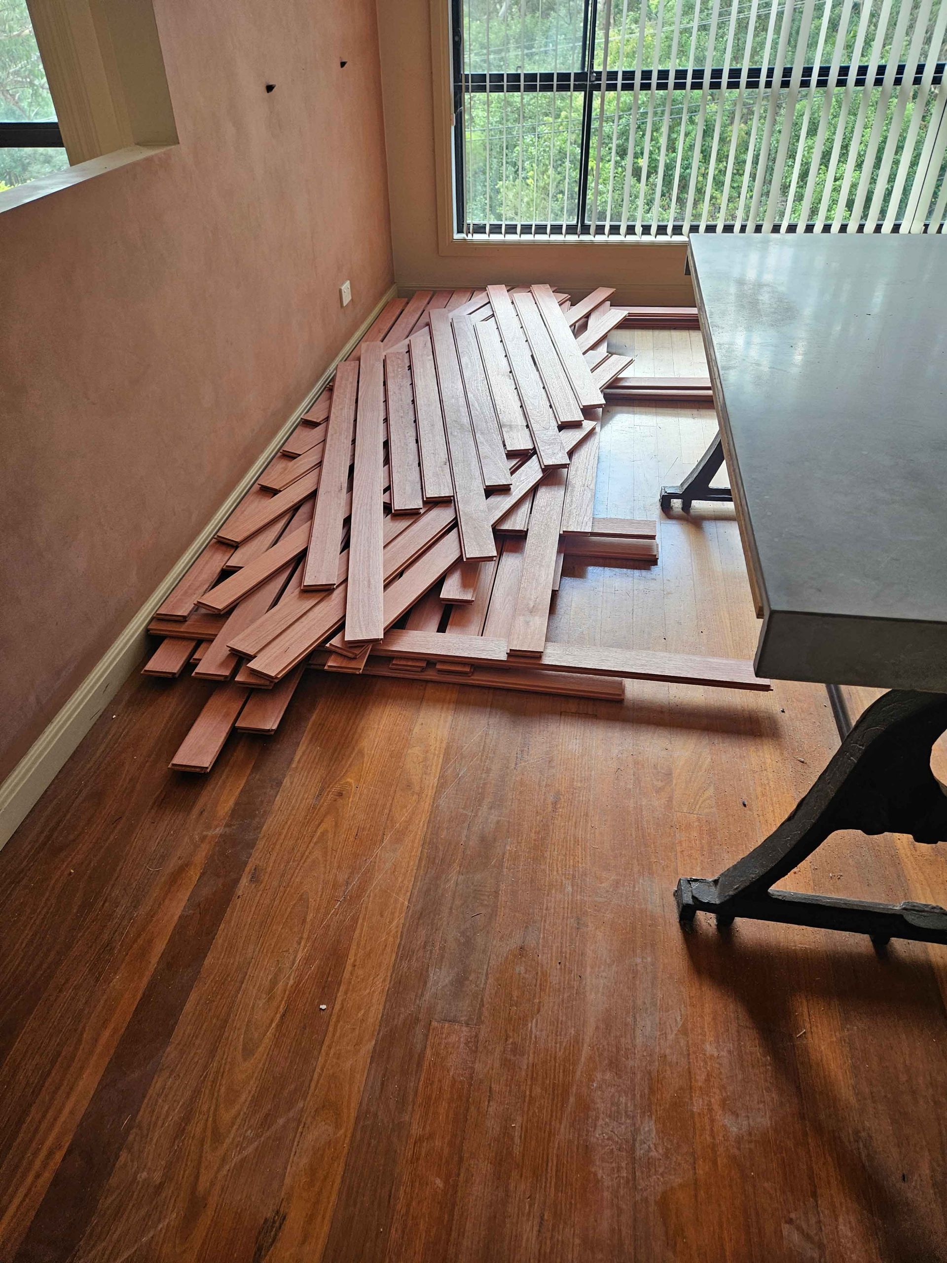 A pile of wood is laying on the floor in a room next to a table.