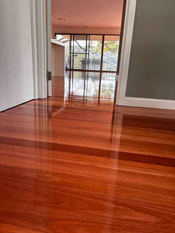 A wooden floor in a room with a door open.