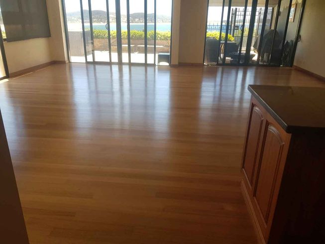 A large empty room with a wooden floor and sliding glass doors.